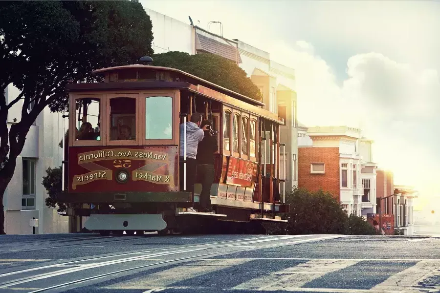 Un téléphérique contourne une colline à San Francisco avec des passagers regardant par la fenêtre.